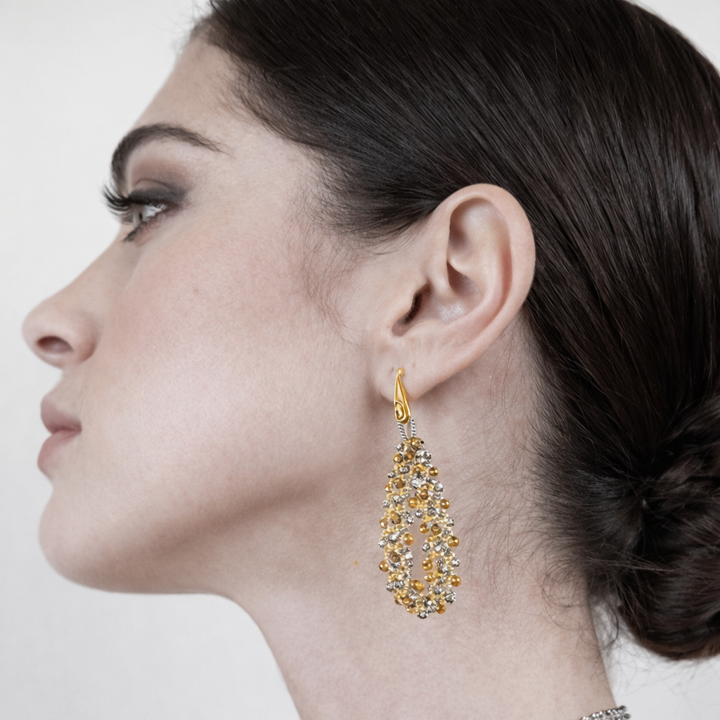 Woman wearing fine gold lace handcrafted earrings on a white background