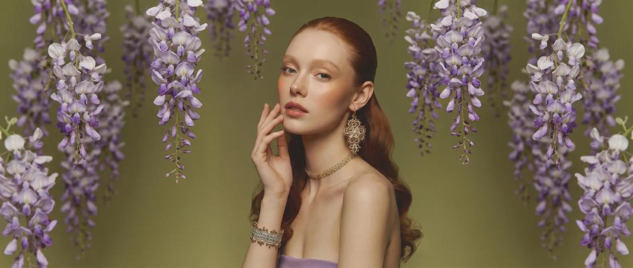 Woman with styled hair and earrings surrounded by wisteria flowers